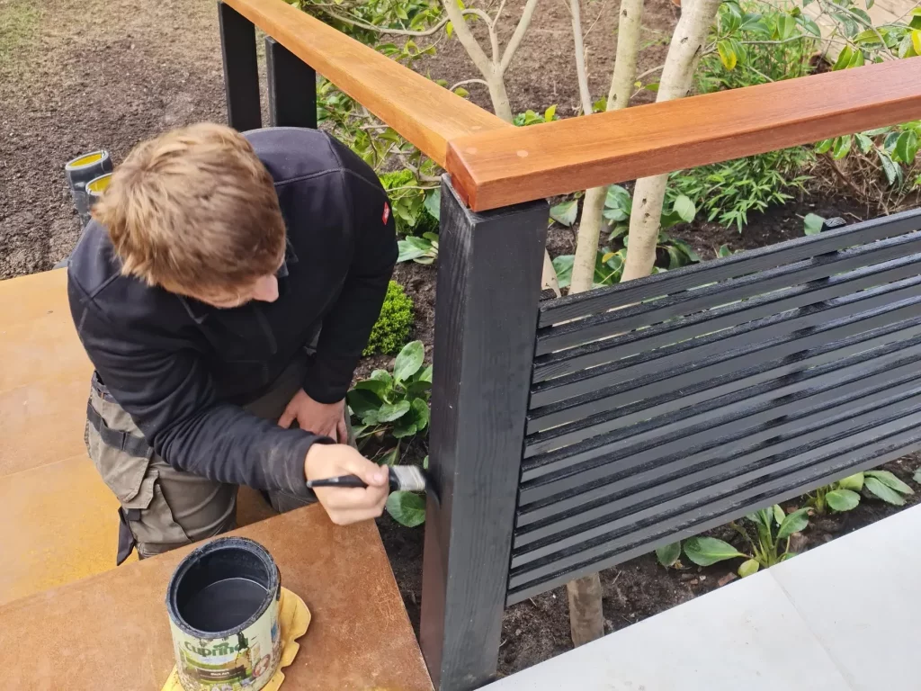 Landigo landscaper painting black timber railings and finishing details in Allerton courtyard garden
