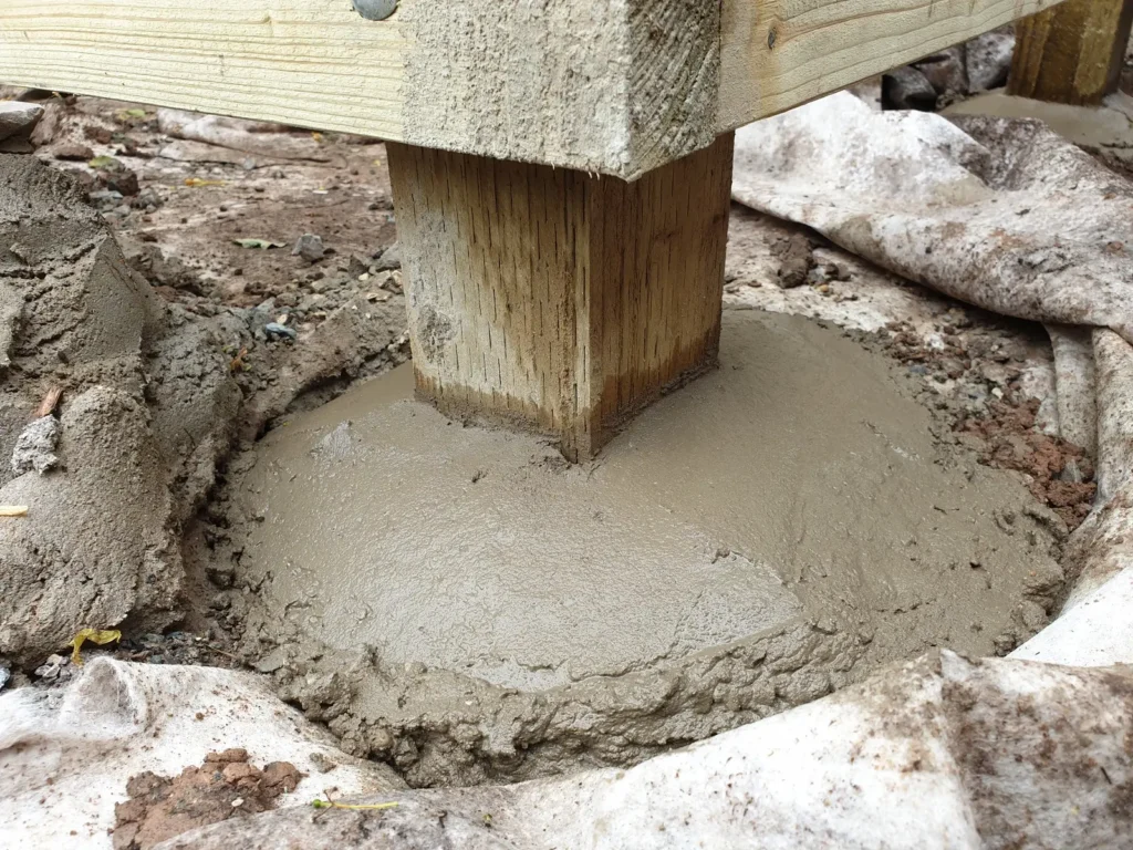 Timber deck post secured in concrete footing to support courtyard pergola structure