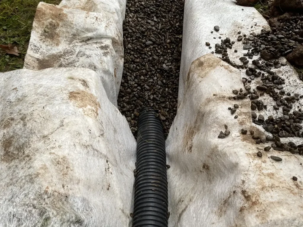 Land drain installation with gravel and geotextile membrane for courtyard garden drainage