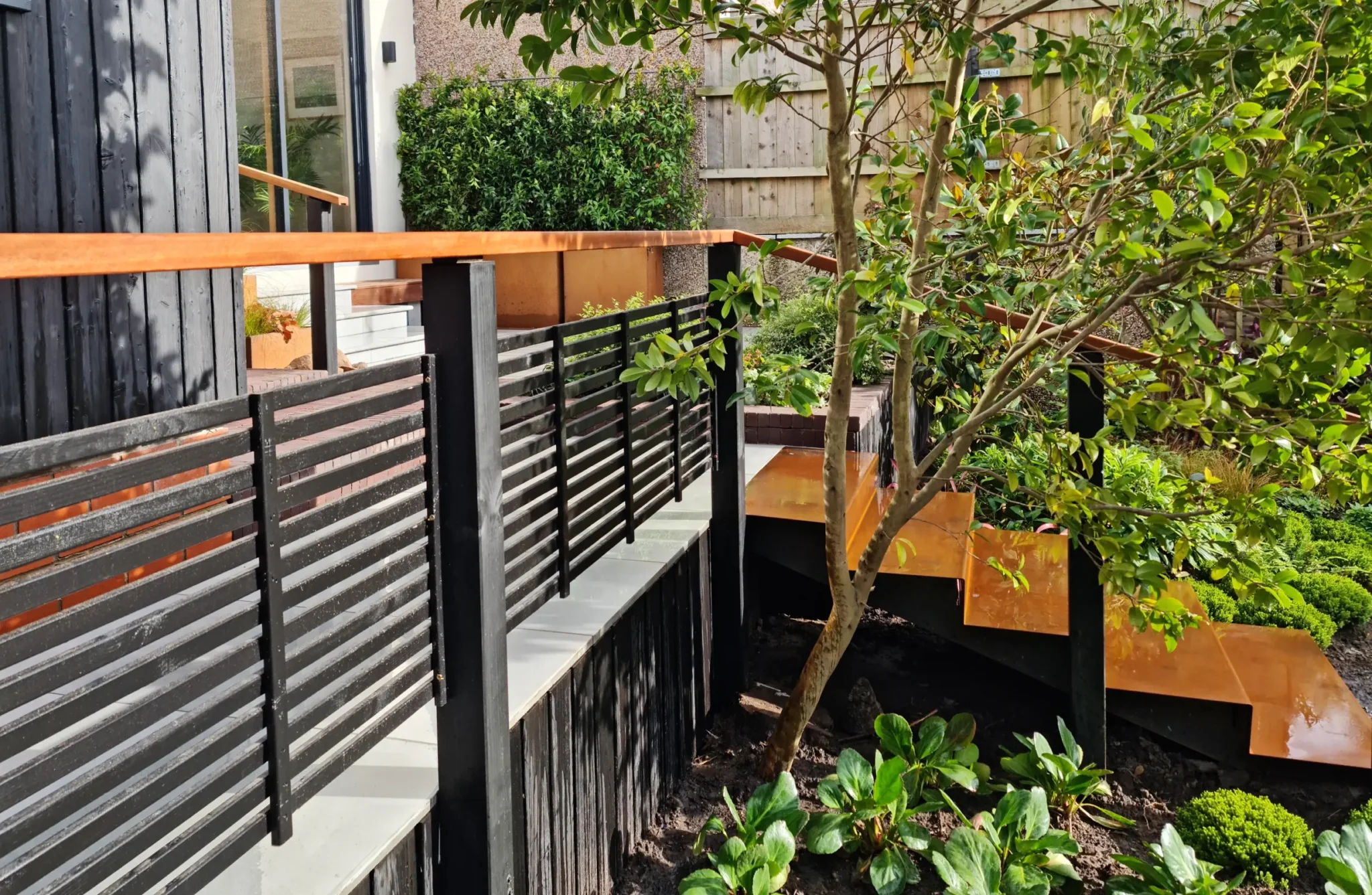 Raised terrace courtyard garden with corten steps and black railings at Nordic Soul Allerton