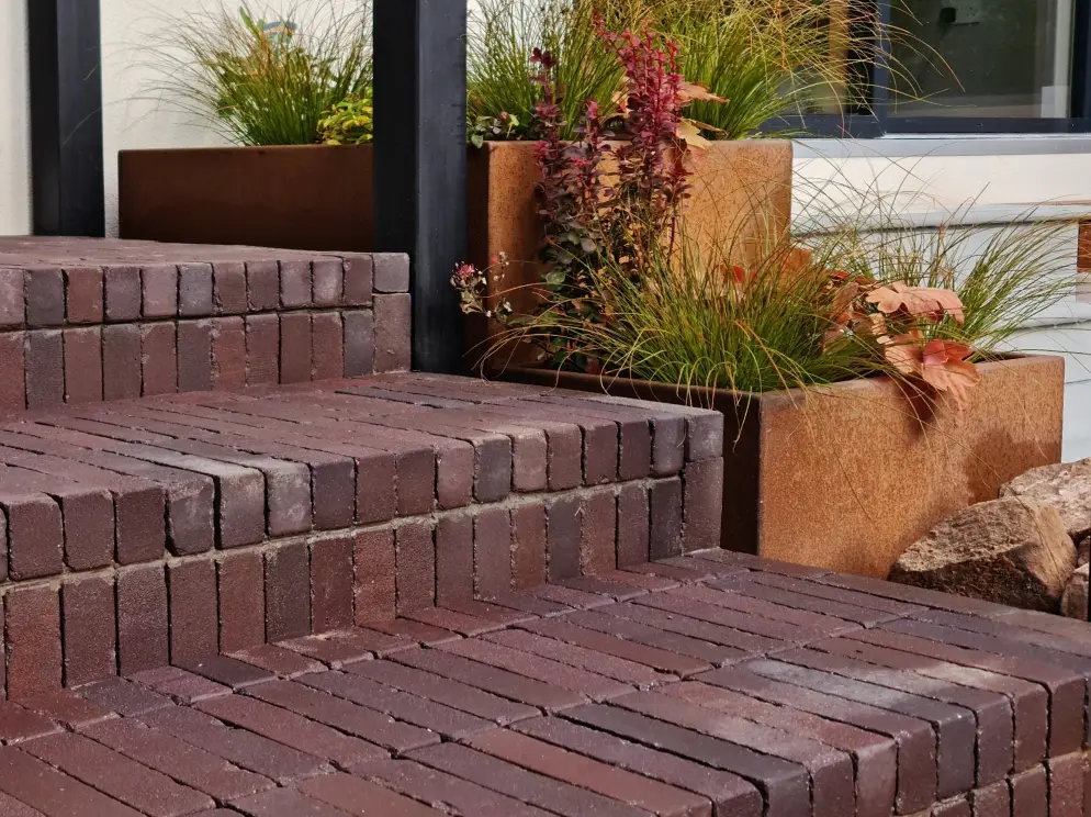 Clay paver terrace steps with corten planters and ornamental grasses in Allerton garden