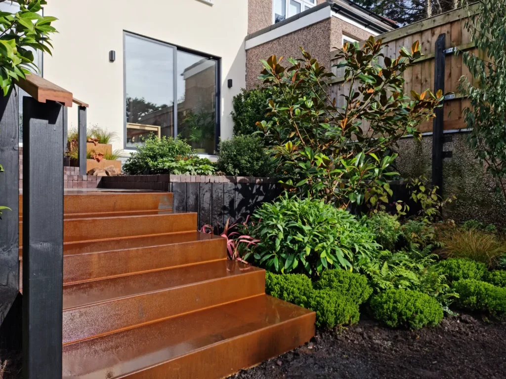 Corten steel garden steps leading through lush planting to a renovated Allerton home