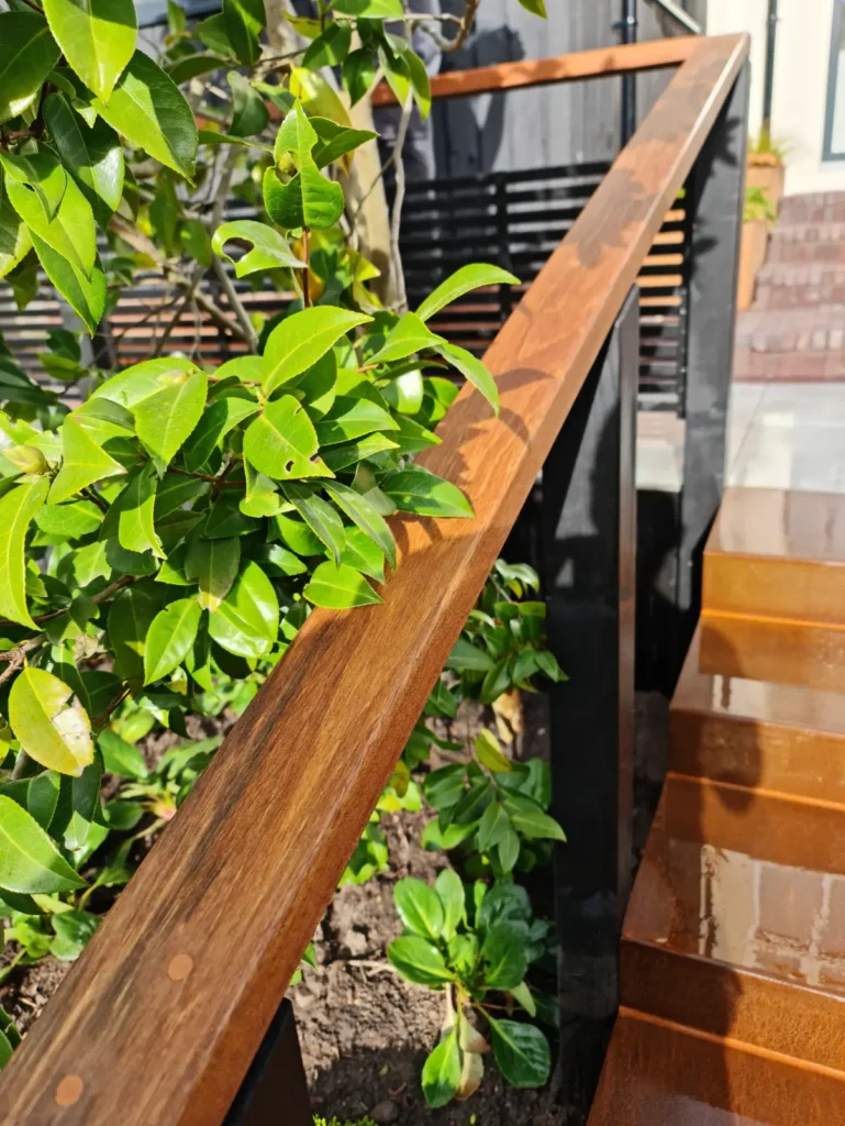 Hardwood handrail and corten steel steps with lush planting in Allerton courtyard garden