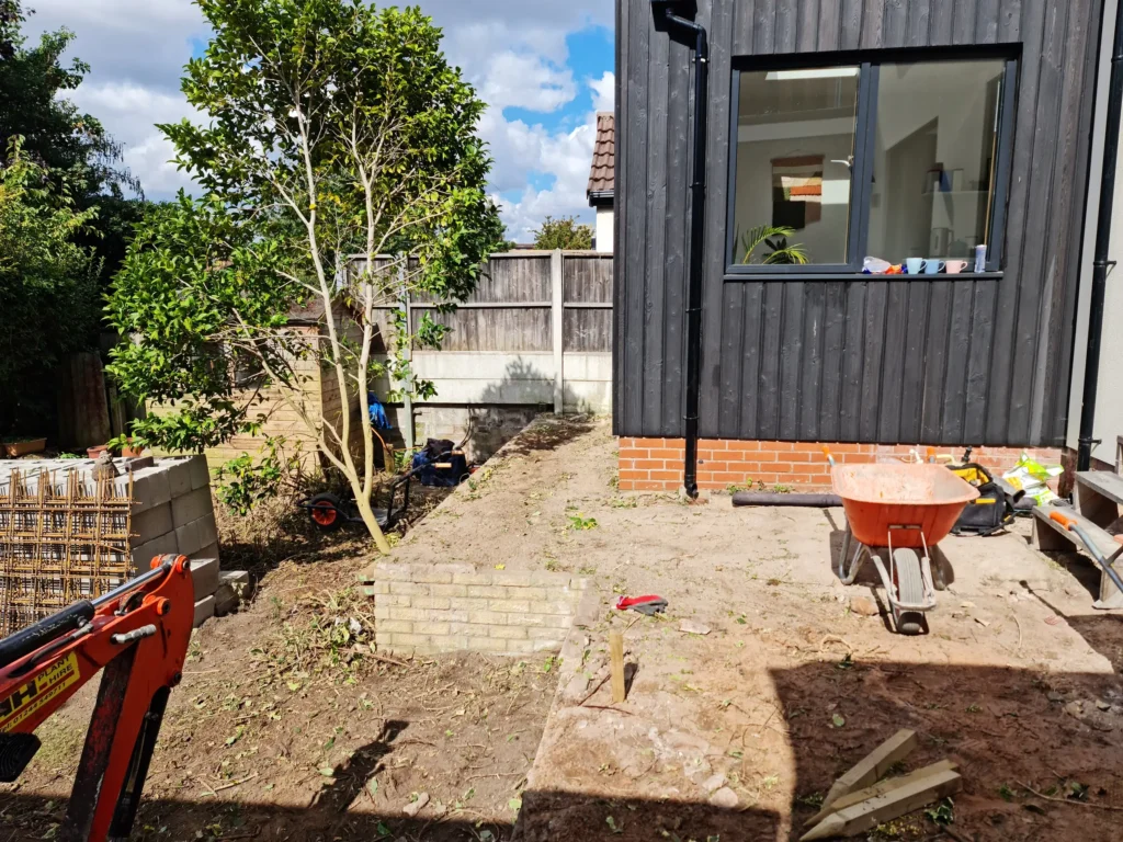 Cleared garden terrace beside renovated Allerton home during landscaping preparation