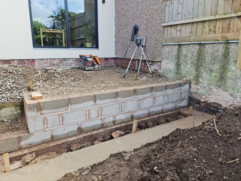 Concrete block retaining wall and laser level setup for raised terrace construction
