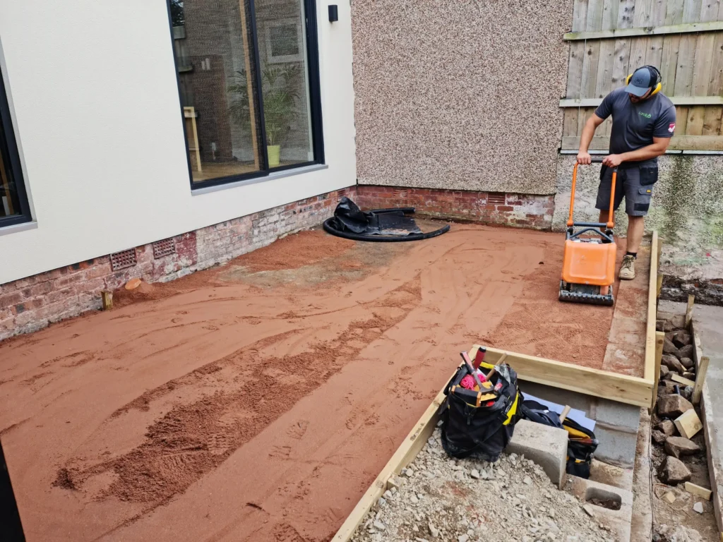 Landigo landscaper compacting terrace subbase before paving installation in Allerton
