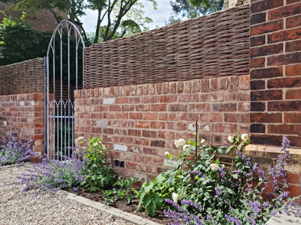 Reclaimed Cheshire brick wall with willow weave screen and soft garden planting