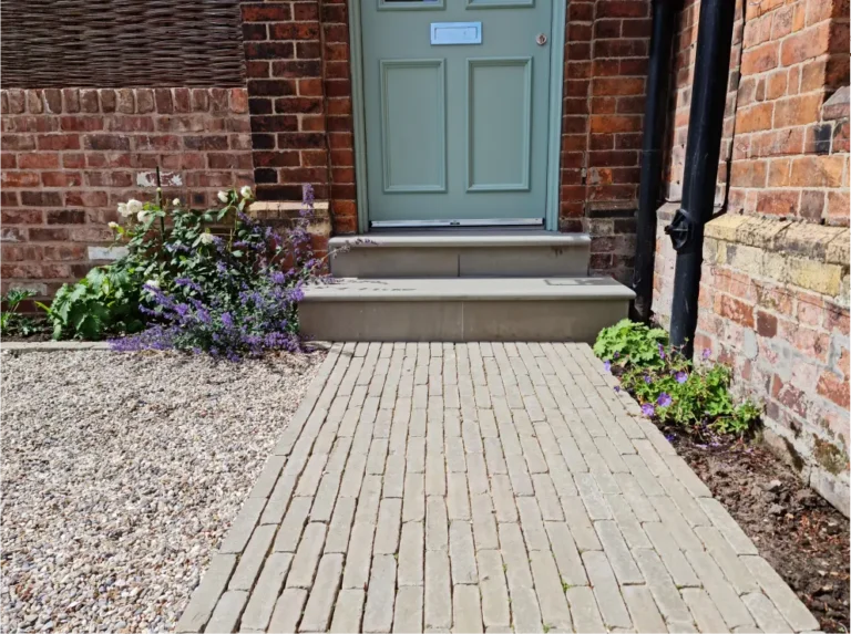Clay paver path with gravel border and flowering plants in Altrincham front garden