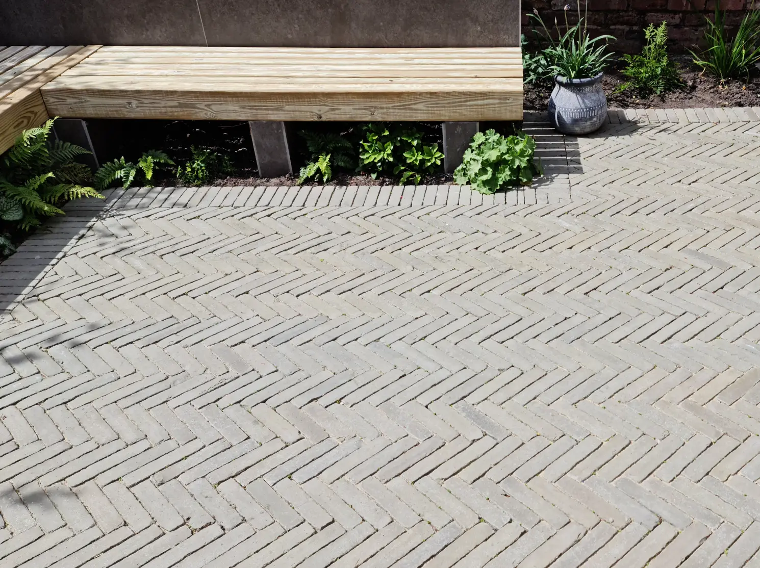 Herringbone clay paver patio with built-in bench and planting in Altrincham garden