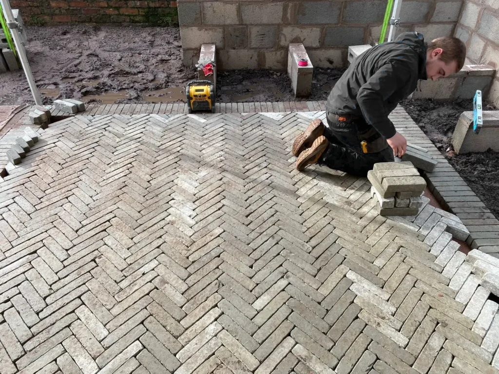 Herringbone clay pavers being installed for outdoor rug effect in Altrincham garden