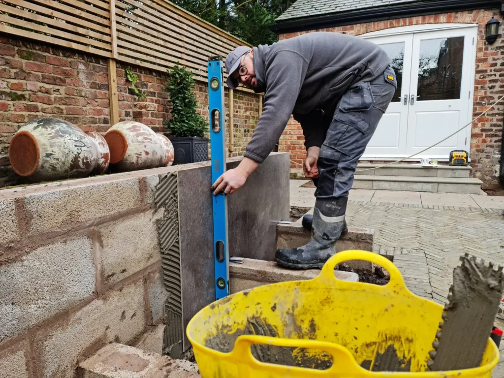 Landigo landscaper checking porcelain-clad garden wall levels during installation