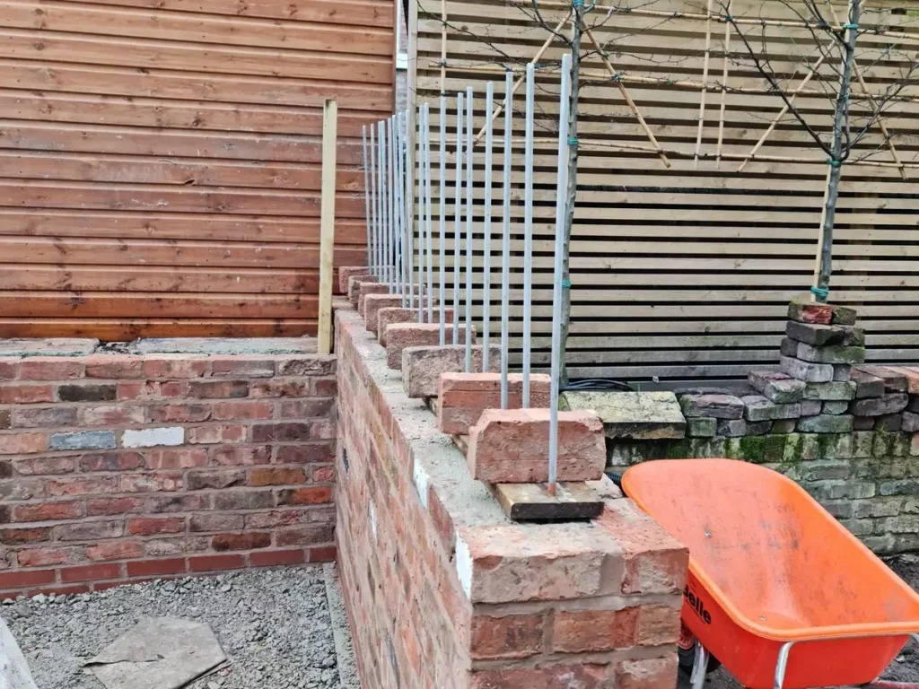 Galvanised steel rods prepared for willow weave screen in reclaimed brick garden wall