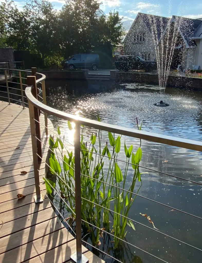 Pool fountain and timber deck walkway with stainless steel railings in Wilmslow garden