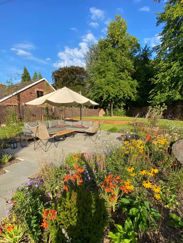 Paved garden seating area with parasols and colourful planting in Wilmslow pool renovation