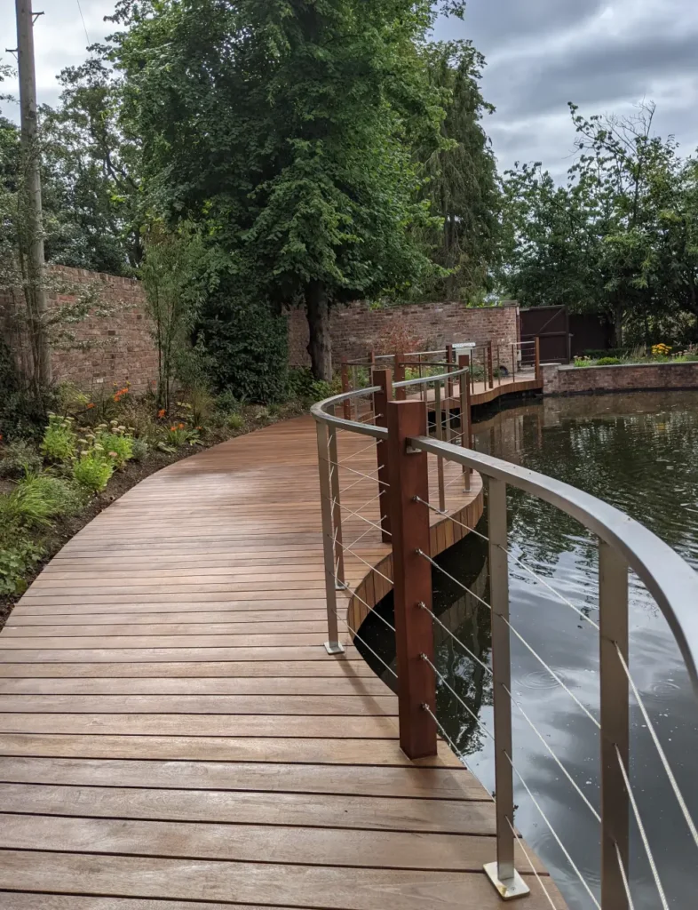 Finished timber deck walkway and stainless steel railings around a restored pool in Wilmslow