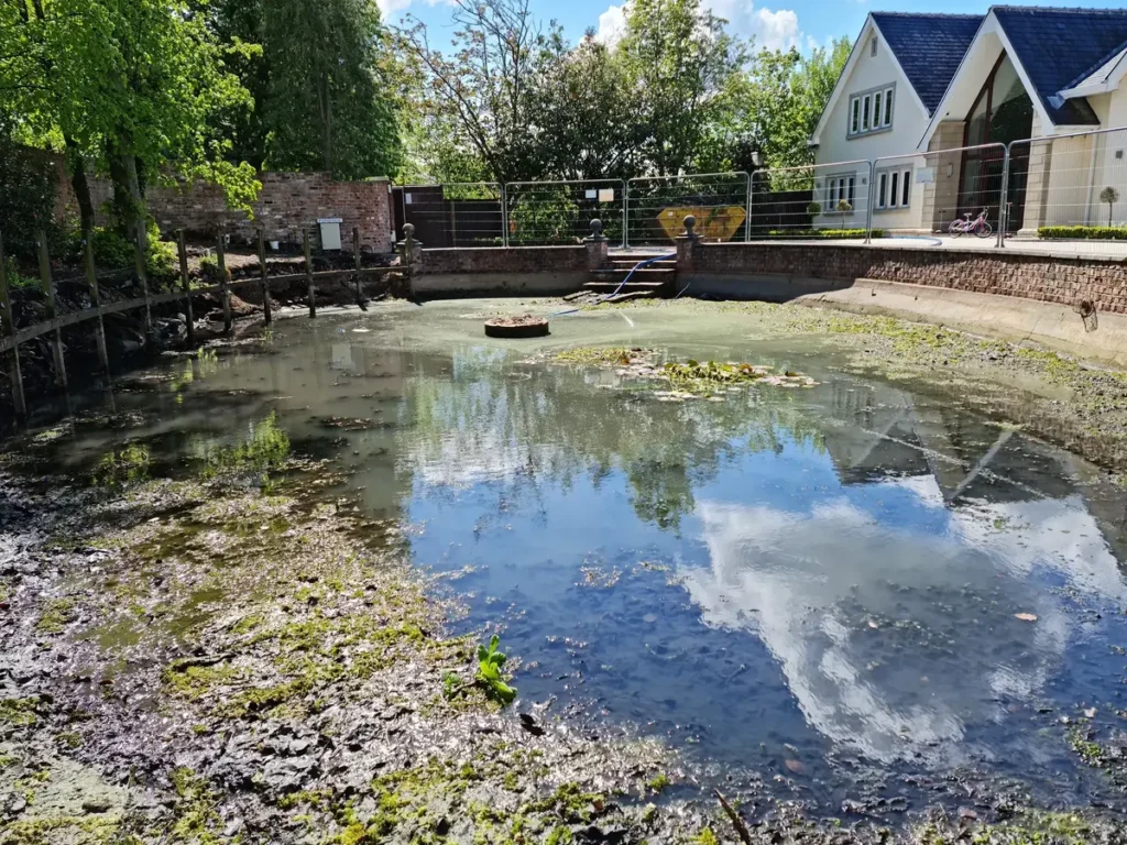 Drained garden pool with debris build-up before restoration work in Wilmslow