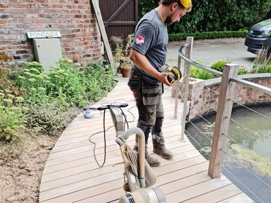 Landigo landscaper sanding timber deck before applying low impact weather sealant