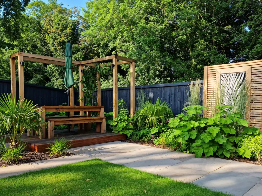 Finished courtyard garden in Malpas with timber pergola, lush planting and sandstone paving