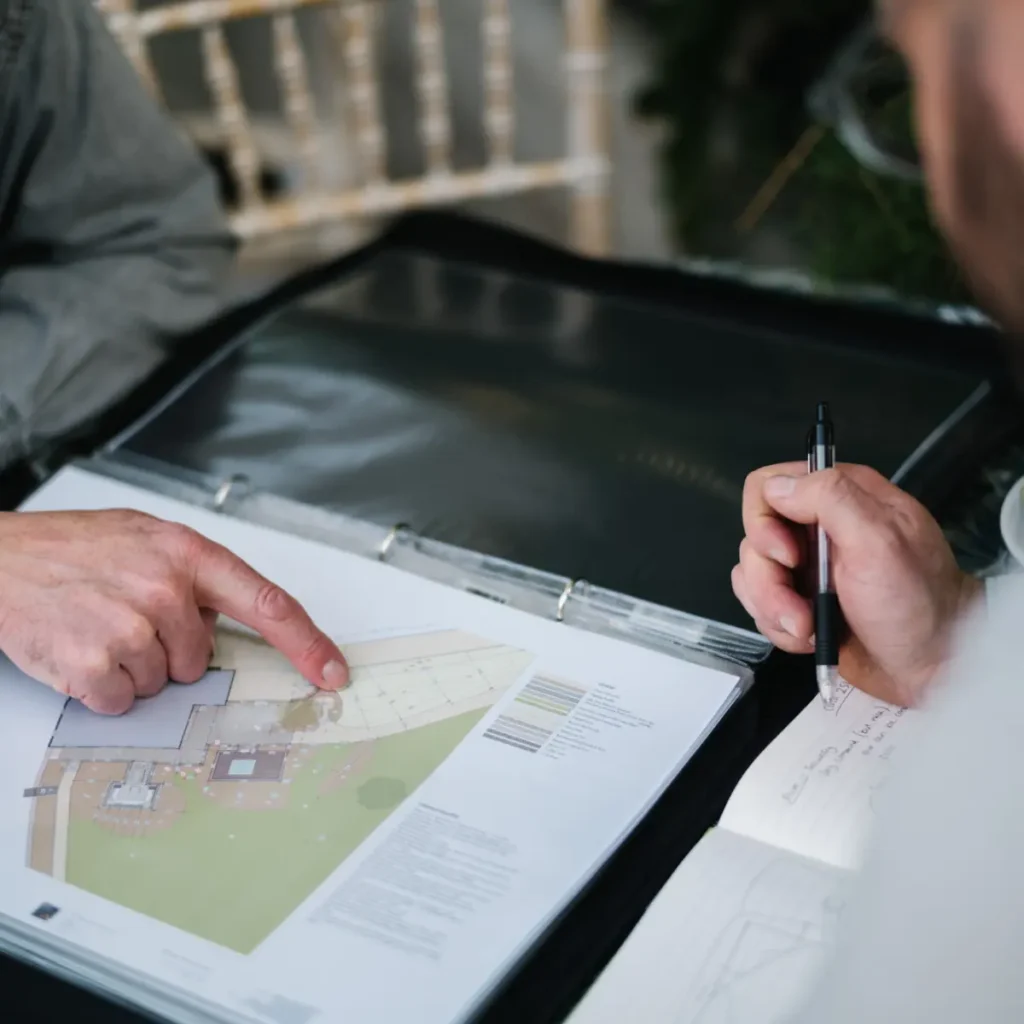 Close-up of hands pointing at a landscape design document during a meeting.