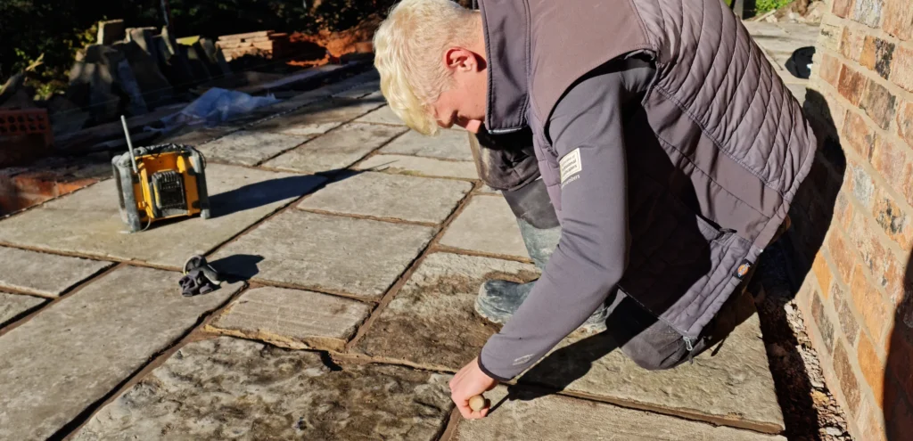 A Landigo construction worker engaged in landscaping work, laying stones on the ground.