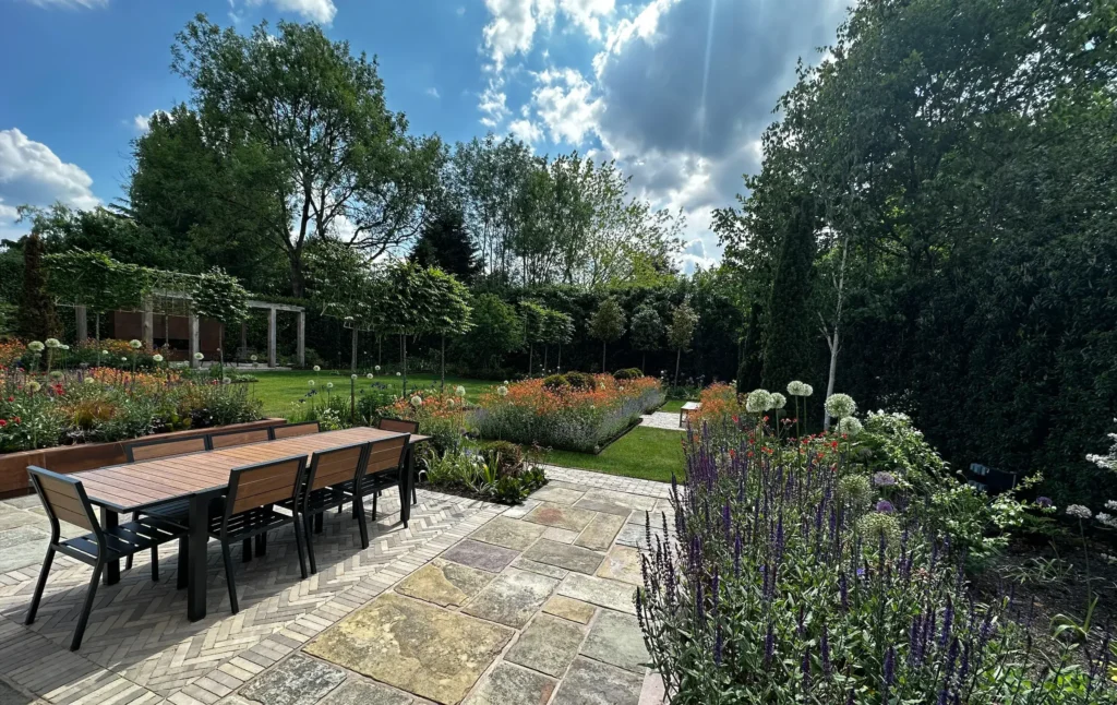 A scenic view of a landscaped garden with colourful flowers and a stone patio.