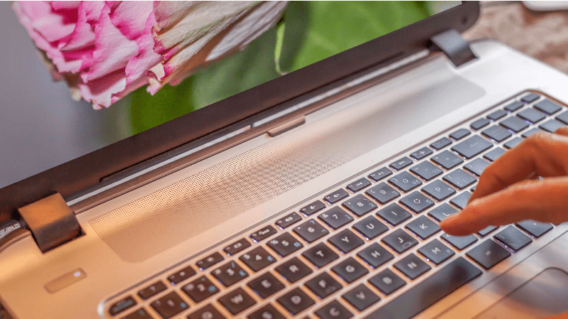 A close-up of a laptop keyboard with a flower background.