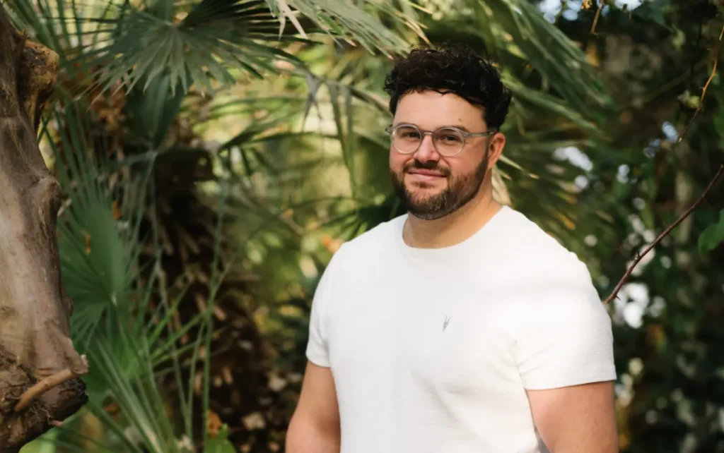 Calum Fraser stands in front of a vibrant green background.