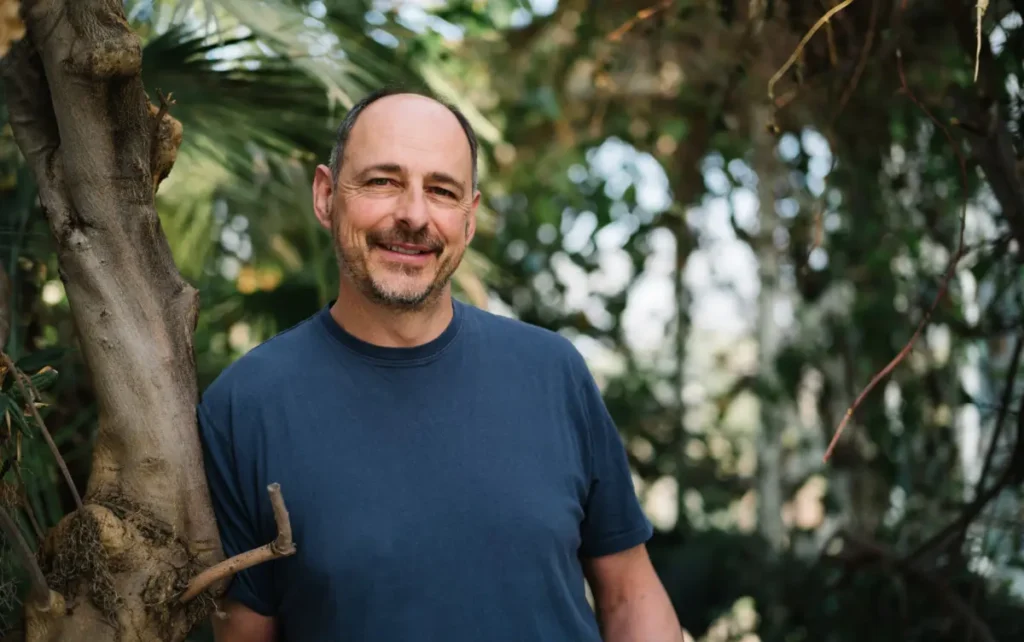 Jason Hinks smiling while leaning against a tree.